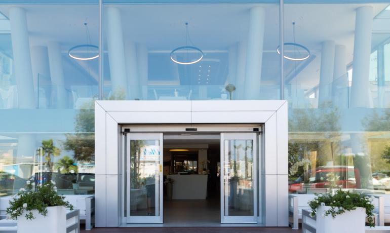 Modern entrance of a building with sliding doors and large windows.