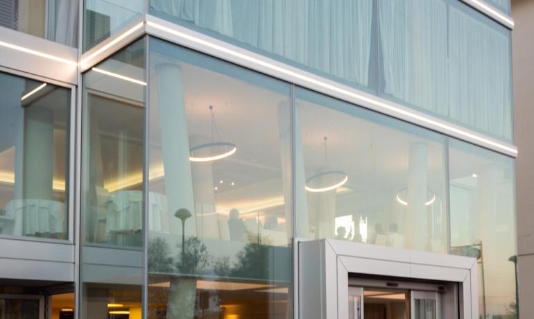 Bâtiment moderne avec façade en verre et mobilier extérieur blanc.