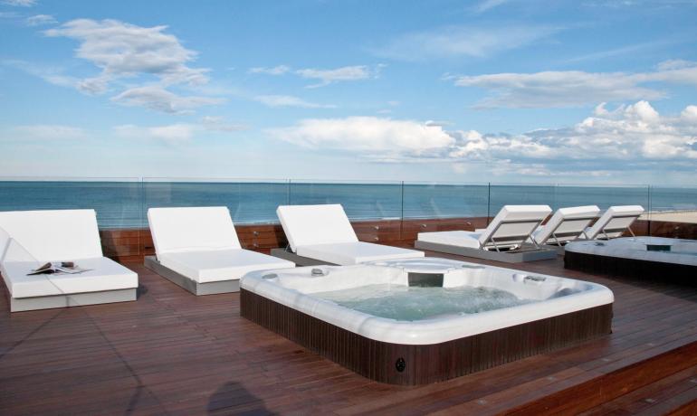 Terrasse mit Liegen und Jacuzzi mit Meerblick.