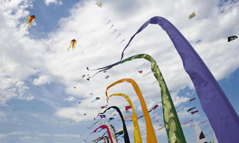 Cerfs-volants colorés volant dans le ciel sous des nuages blancs.