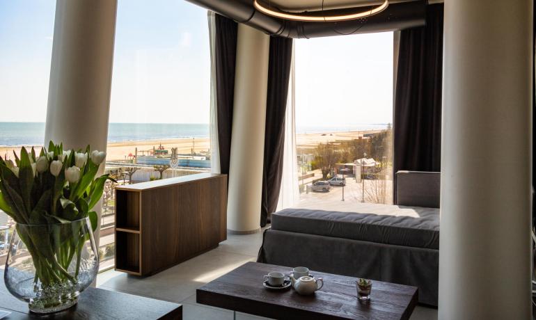 Modern interior with sea view, flowers, and tea cups.