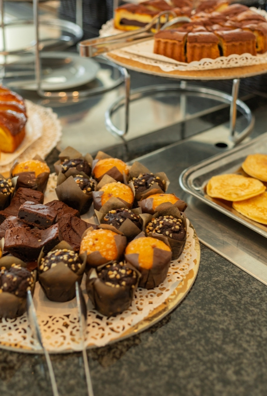 Assortimento di dolci: muffin, brownies e torte su vassoi decorati.