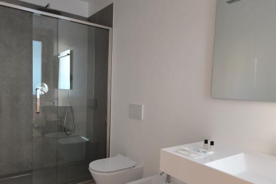 Bagno moderno con doccia in vetro, lavabo bianco, WC e bidet.