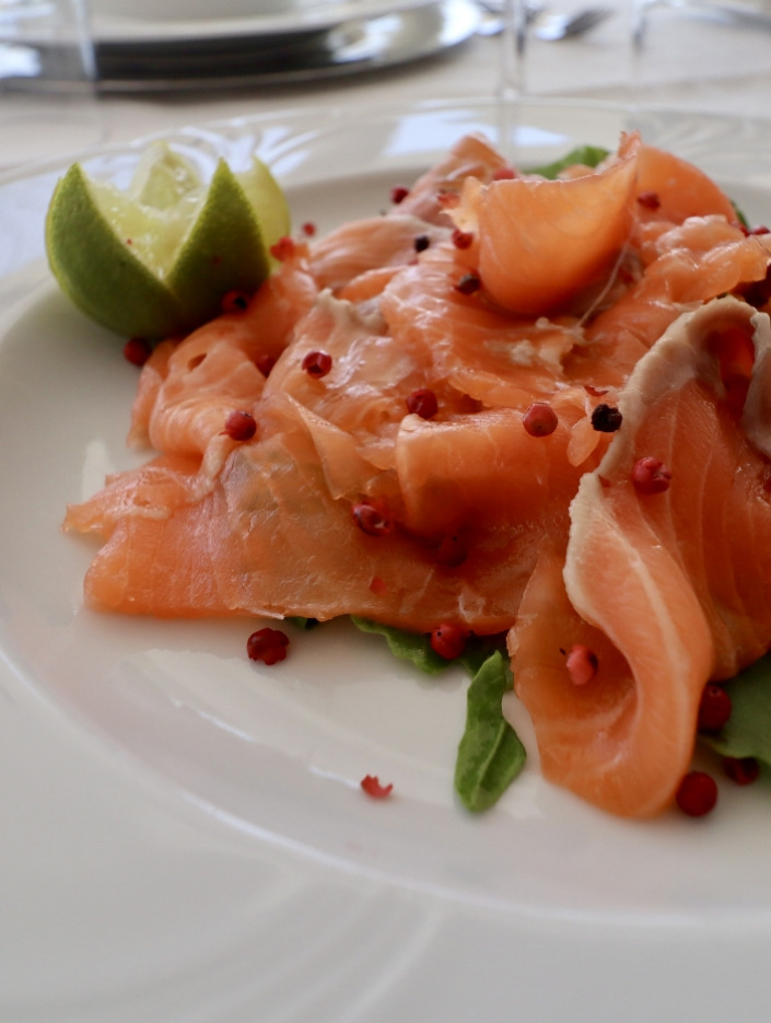 Salmone affumicato con pepe rosa e lime su letto di rucola.