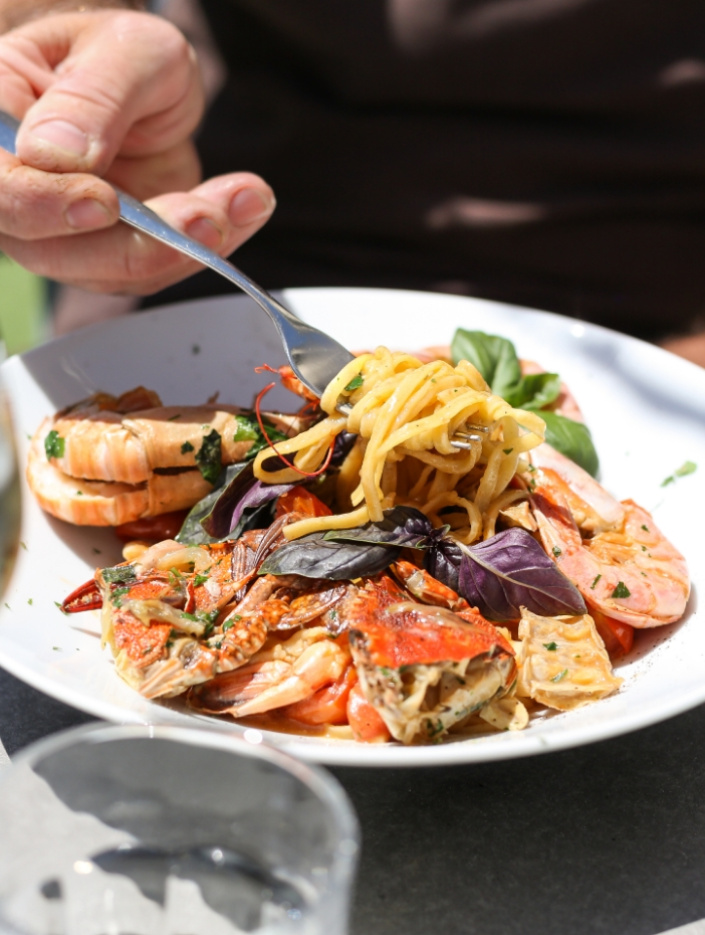 Piatto di pasta ai frutti di mare con gamberi e granchio, guarnito con basilico.