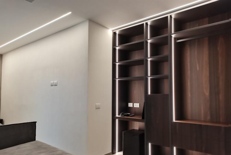 Camera moderna con scaffali in legno e illuminazione a LED.