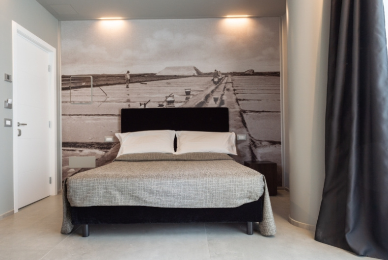 Camera moderna con letto matrimoniale e murale di paesaggio retroilluminato.