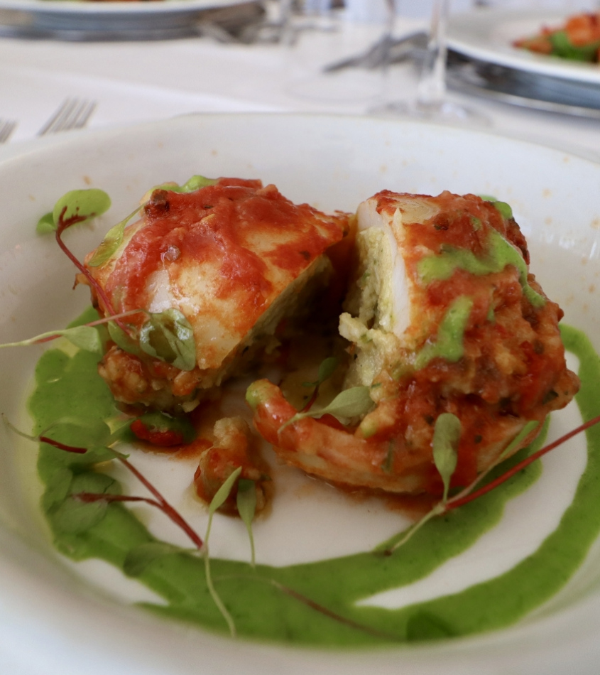 Piatto gourmet con ripieno, salsa verde e decorazioni di germogli.